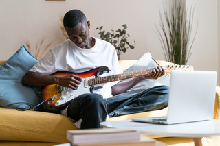 Rapaz dedilhando sua guitarra